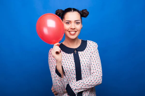 Femme souriante tenant un ballon rouge à la main — Photo