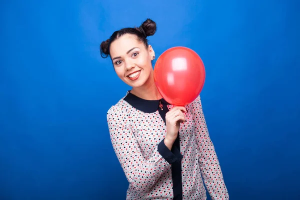 Femme souriante tenant un ballon rouge à la main — Photo