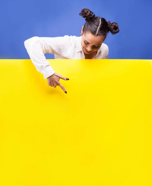 Mujer sonriente poiting a un cartel amarillo — Foto de Stock