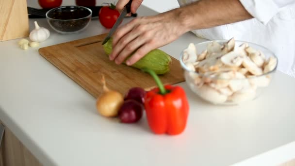 Koch nimmt einen Kürbis vom Tisch und beginnt ihn zu schneiden — Stockvideo