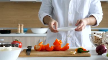 Erkek mutfak arkasından gelir ve bir tabak içinde tatlı kırmızı yetkin yerleştirir