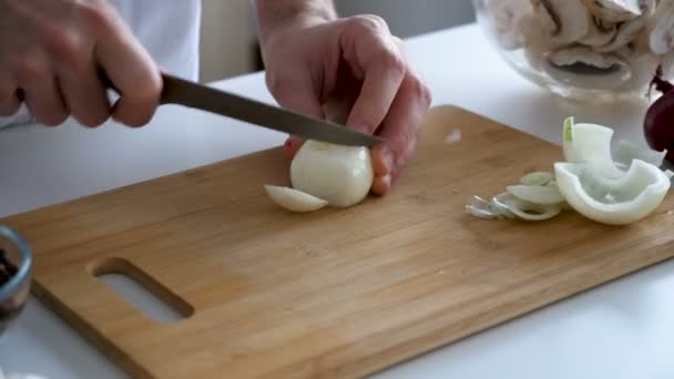 Maschio cuoco taglia cipolla su tavola di legno — Video Stock