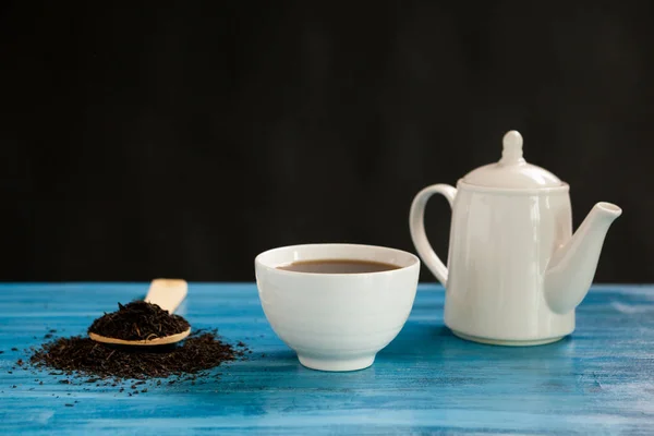 Tè caldo accanto a un cucchiaio con foglie di tè — Foto Stock