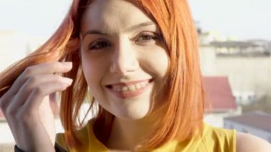 Gün batımında saçları ile oynarken Kızıl saçlı kadın