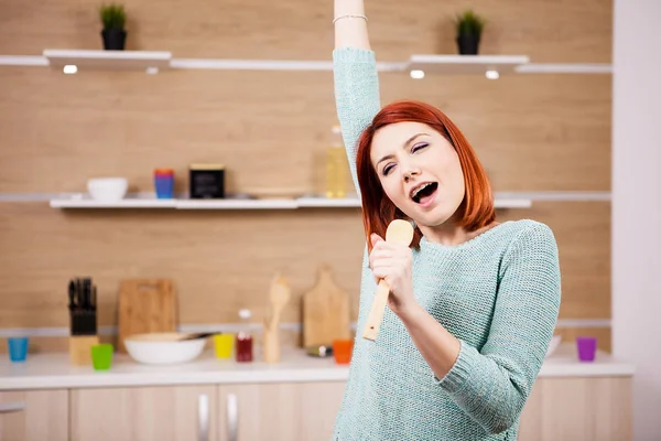 Mulher ruiva muito feliz cantando na cozinha — Fotografia de Stock