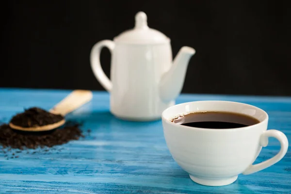 Горячий чай рядом с ложкой с чайными листьями — стоковое фото