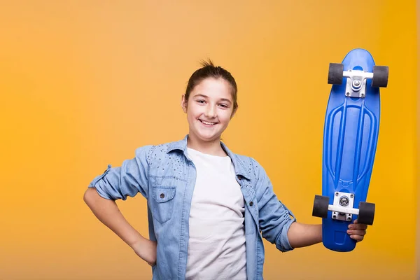 Усміхнена дівчина-підліток дивиться на камеру і тримає синій ковзаняр — стокове фото