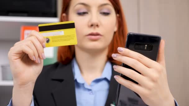 Empresaria mirando su tarjeta de crédito e introduciendo los datos en el teléfono inteligente — Vídeo de stock