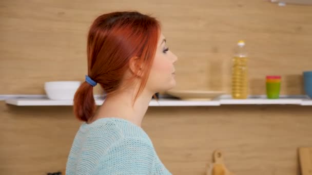 Женщина идет на кухню и открывает жалюзи, чтобы посмотреть через них — стоковое видео