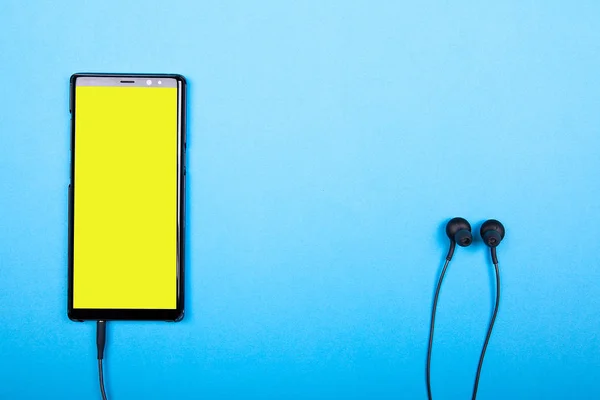 Вид сверху смартфона с желтым экраном, подключенным к наушникам — стоковое фото