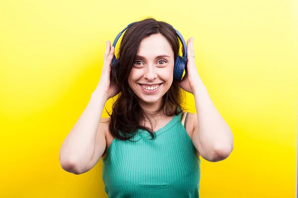 Mulher excitada ouvindo música em seus fones de ouvido azuis — Fotografia de Stock