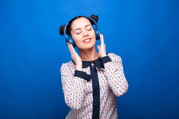 Leende kvinna lyssnar på musik via hörlurar — Stockfoto