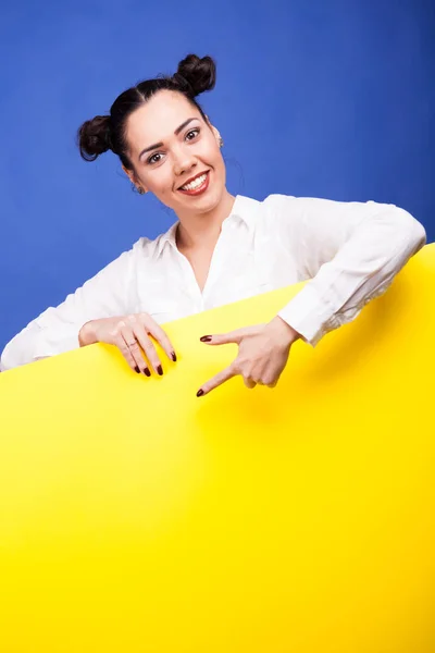 Heureuse femme souriante pochant sur une bannière jaune — Photo