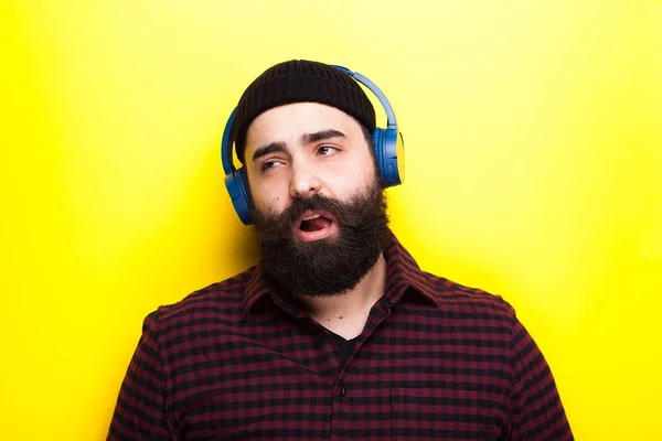 Hipster com um fone de ouvido sem fio azul ouvindo música — Fotografia de Stock