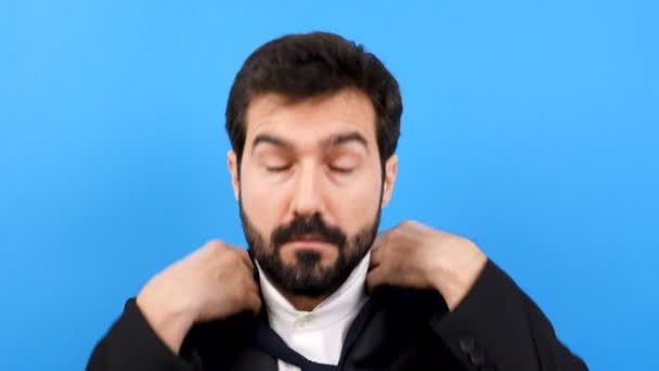 Geschäftsmann auf blauem Hintergrund arrangiert seine Krawatte — Stockvideo