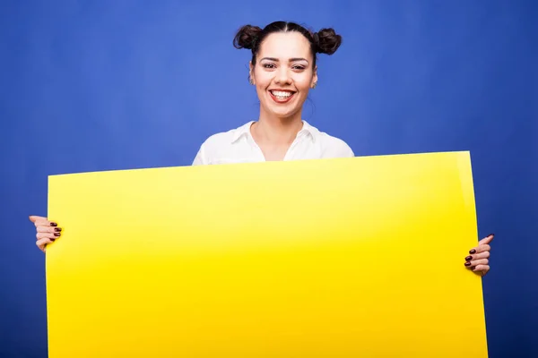 Feliz sorrindo mulher segura um cartaz amarelo nas mãos — Fotografia de Stock