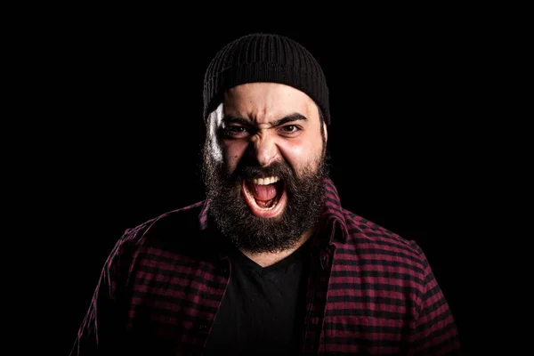 Бородатый мужчина кричит в гневе на черном фоне — стоковое фото