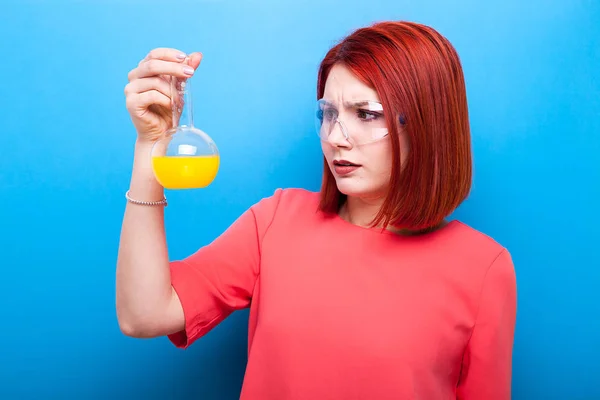 Redhair nerd with a flask of yellow liquid in her hand — Stock Photo, Image