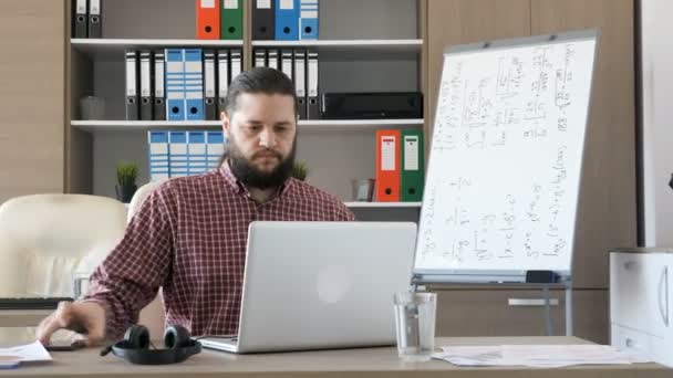 Man komt aan het Bureau, zet de hoofdtelefoon op zijn oren en begint te praten aan een klant — Stockvideo