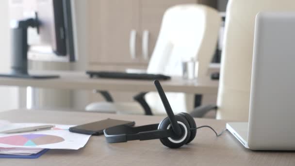 Auriculares tumbados en el escritorio en la oficina de atención al cliente — Vídeos de Stock