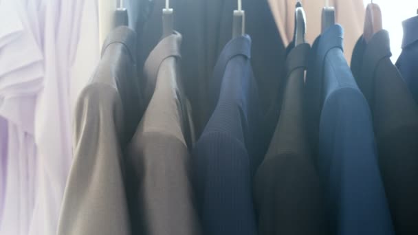 Hanger met zakelijke kleding naast een venster in een winkel — Stockvideo