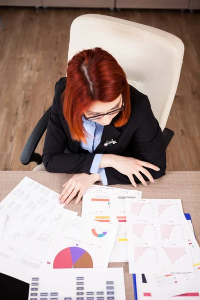 Redhead businesswomna guardando diagrammi e grafici — Foto Stock