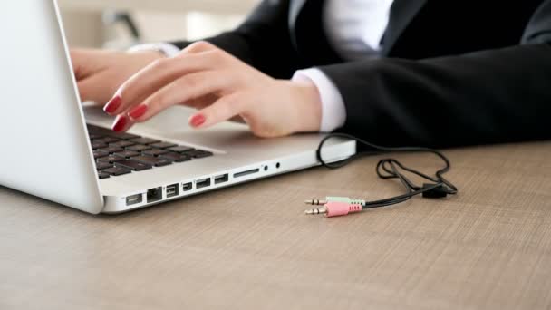 Frau tippt am Laptop und steckt dann das Kabel in den Computer — Stockvideo