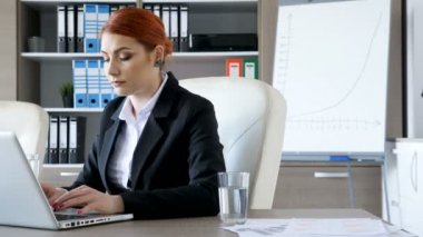 İş kadını ofiste dizüstü bilgisayarda yazarak onun masasında
