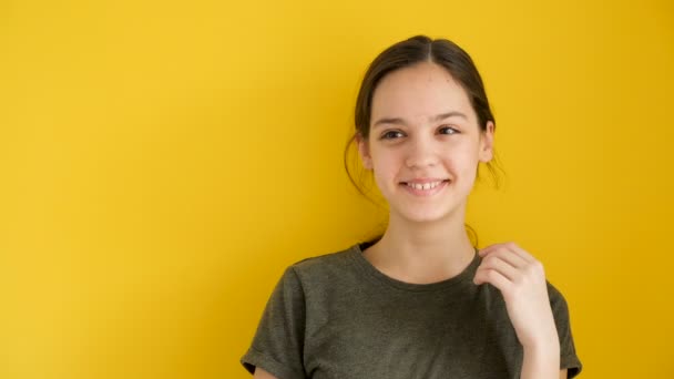 Attractive teenage girl laughing on yellow background — Stock Video