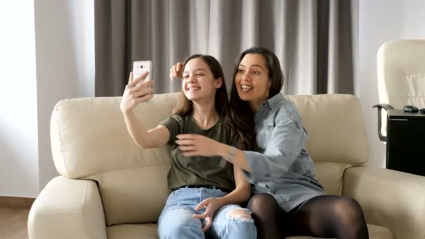 Beautiful sisters in the living room on the couch taking a selfie — Stock Video