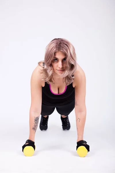 Fit woman in sport clothes doing pushups on dumbbells — Stock Photo, Image