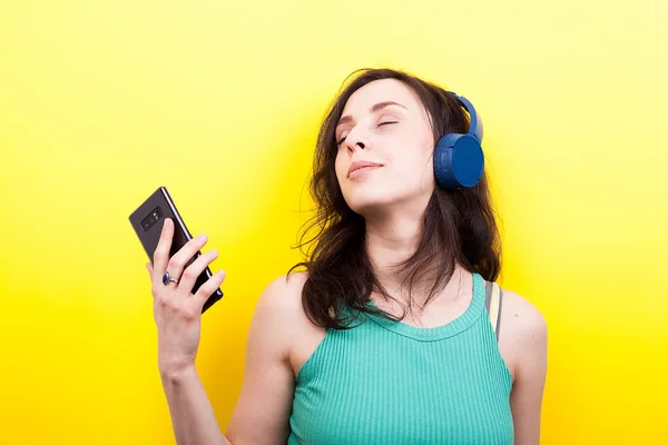Мечтающая молодая женщина слушает музыку со смартфоном в руке — стоковое фото