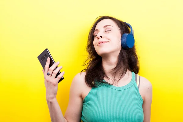 Menina sorridente com um smartphone nas mãos ouvindo música — Fotografia de Stock