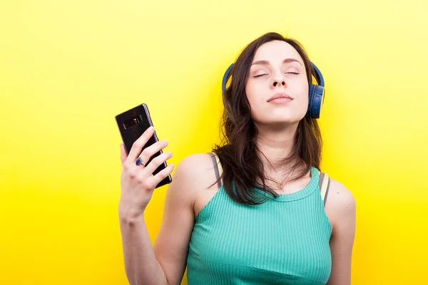Mujer con los ojos cerrados y un smartphone en la mano escuchando mus —  Fotos de Stock