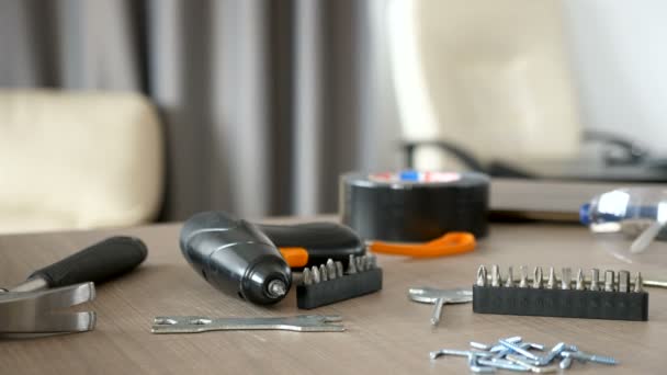 Electric screwdriver lying on a table next to other furniture assemble equipment — Stock Video