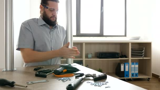 Чоловік кладе захисні окуляри і починає розбирати меблі — стокове відео