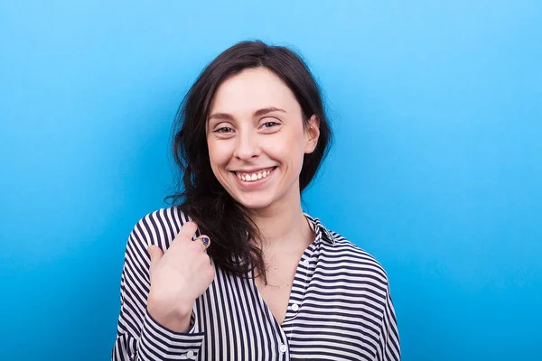 Frau lächelt in die Kamera auf blauem Hintergrund — Stockfoto