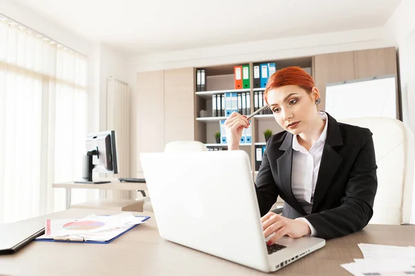 Mooie roodharige zakenvrouw werken op de laptop — Stockfoto