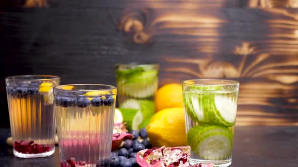 Zelfgemaakte limonade gemaakt van verschillende vruchten en berried en brillen met detox komkommer water — Stockvideo