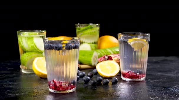 Чотири склянки з детоксикатною водою з фруктами та ягодами, інші з огірків — стокове відео