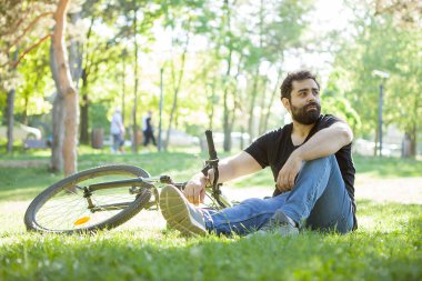 Genç adam uzakta çimenlerin üzerinde dinlenme sırasında görünüyor