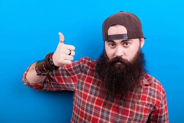 Hipster homem com barba longa mostrando um polegar até a câmera — Fotografia de Stock