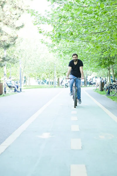 Joven barbudo montando en bicicleta en el parque — Foto de Stock