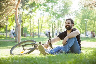 Sakallı adamın yere dinlenme bisikletine yanında