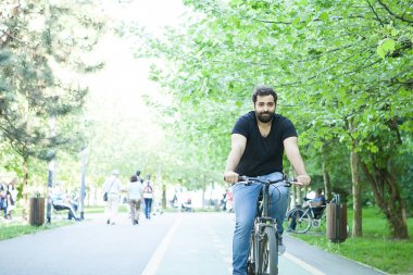 Genç adam parkta Bisiklete binmek sakallı