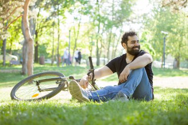 Çimenlerin üzerinde dinlenme bisikletine yanındaki adam