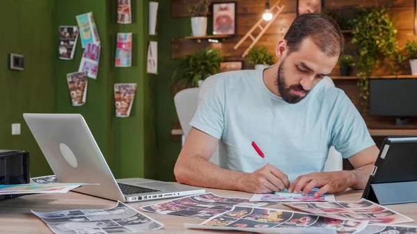 Young designer who makes some notes on one of the dozens of sheets he has on the desk — 图库照片