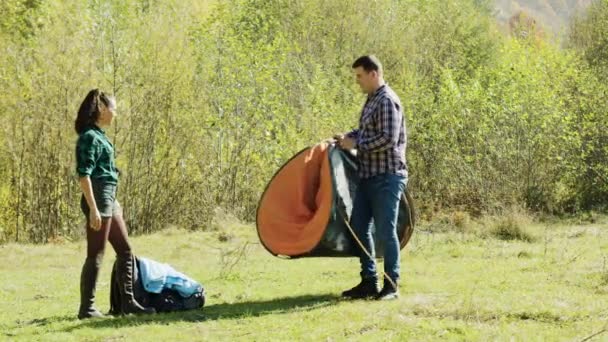 Aantrekkelijke jonge man en zijn vriendin opzetten tent voor camping — Stockvideo