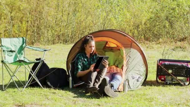 Belle jeune copine en utilisant sa tablette devant la tente de camping — Video