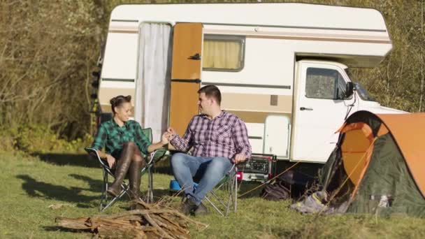 Hipster casal sentado em seus assentos de acampamento e de mãos dadas — Vídeo de Stock